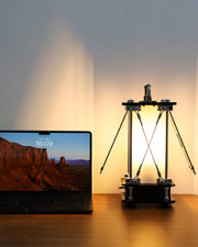 Laptop on a desk with a lamp casting light on a wall