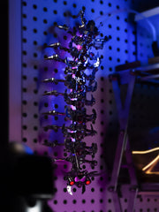 A biomechanical sculpture featuring a vertical array of mechanical parts with a futuristic aesthetic, illuminated by colored lights.