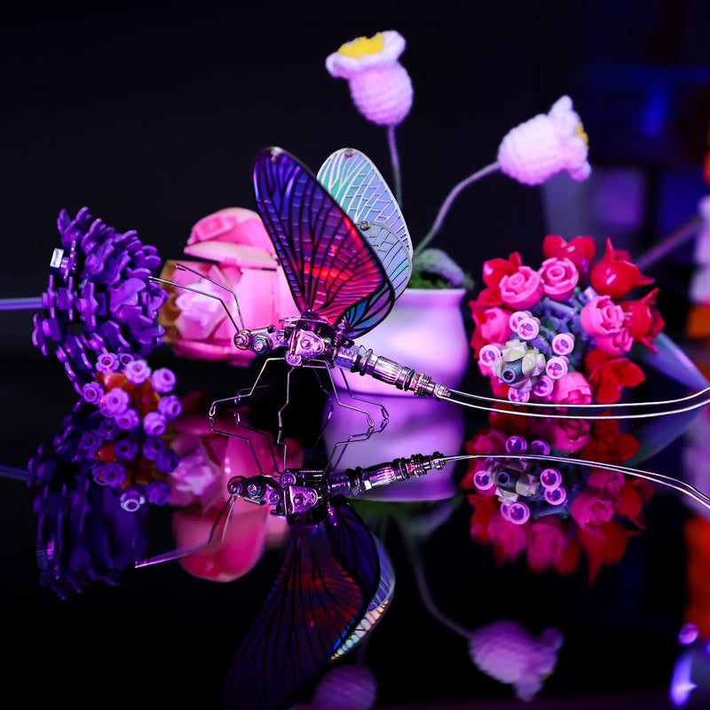Colorful butterfly-shaped object with a reflective surface, surrounded by flowers on a dark background