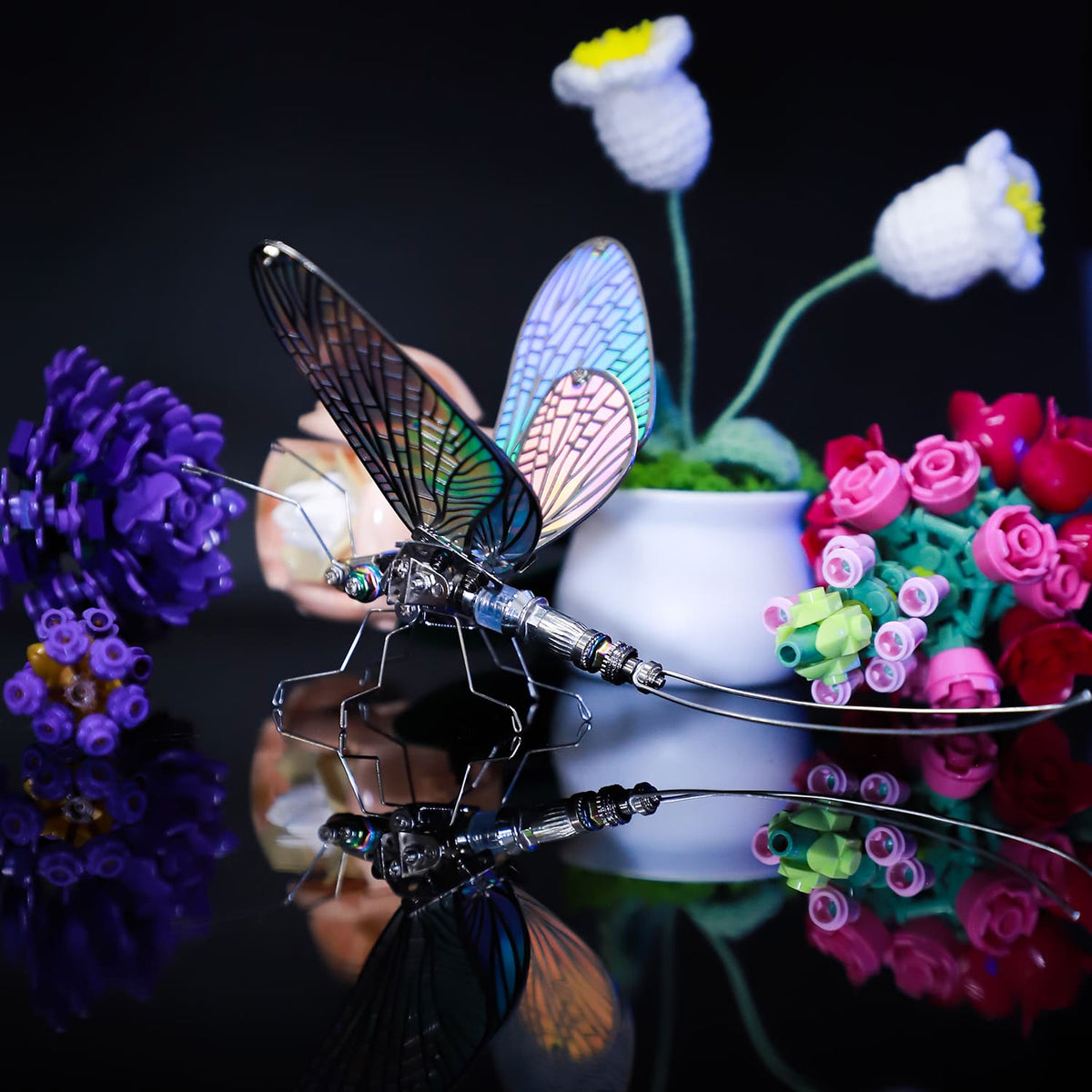 Decorative butterfly with colorful wings on a reflective surface surrounded by flowers.