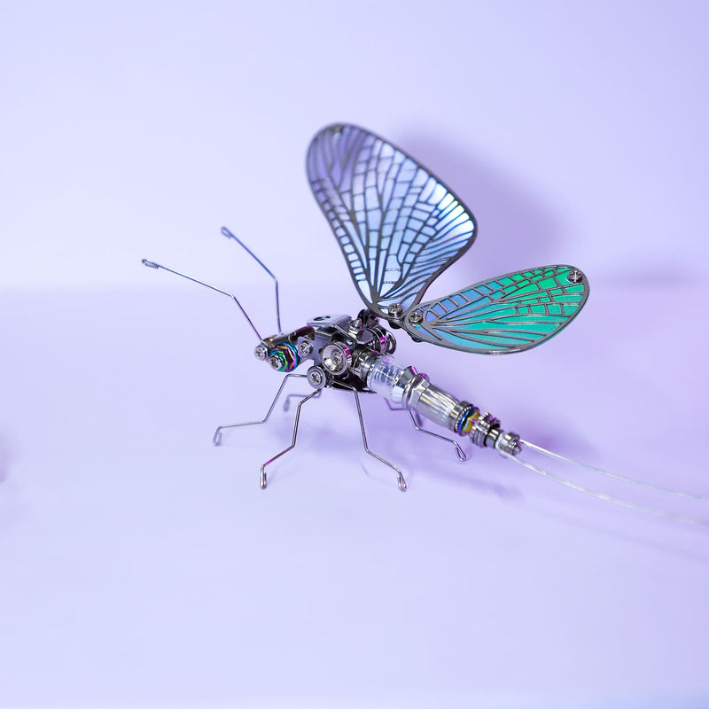 Metallic insect model with blue and green wings on a light purple background