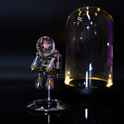Decorative figure with a crystal ball under a glass dome on a dark background