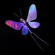 Dragonfly-shaped toy with glowing purple and blue wings on a black background