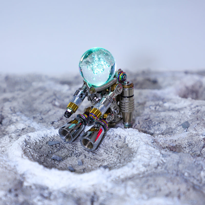 Small robot with a glowing blue sphere on a textured surface