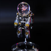 Metallic robot sculpture with a glass ball on a reflective surface