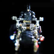 Batman action figure on a motorcycle with lights against a dark background