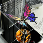 Colorful butterfly-shaped clock on a metallic stand with books in the background