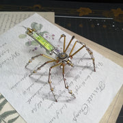 Metallic spider-like object on a piece of paper with cursive writing