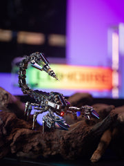 Metallic scorpion sculpture on a dark surface with a colorful blurred background